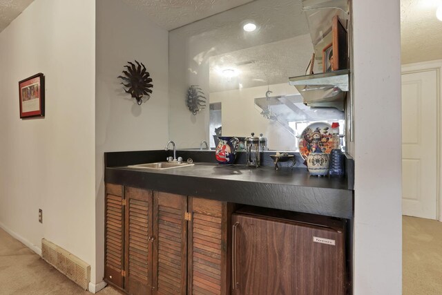 bar featuring a sink, visible vents, carpet floors, and a textured ceiling