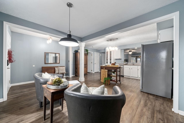 living room with decorative columns, baseboards, dark wood finished floors, and a ceiling fan