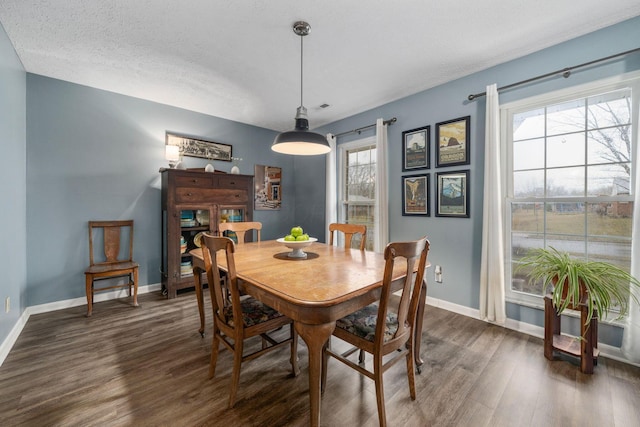 dining space with dark wood-style flooring, a textured ceiling, and baseboards