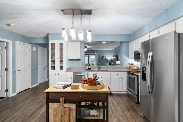 kitchen with dark wood finished floors, stainless steel appliances, white cabinetry, a sink, and a textured ceiling