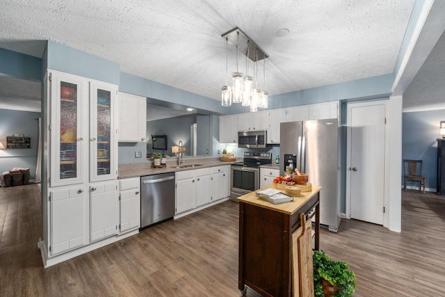 kitchen with a center island, dark wood finished floors, appliances with stainless steel finishes, white cabinets, and a sink