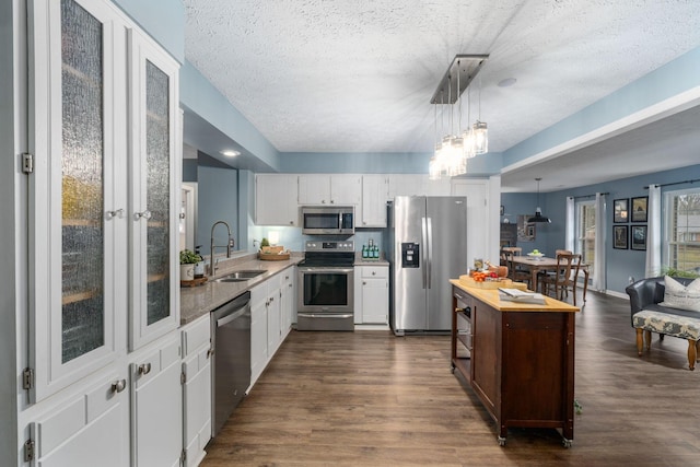 kitchen with dark wood finished floors, stainless steel appliances, light countertops, white cabinetry, and a sink