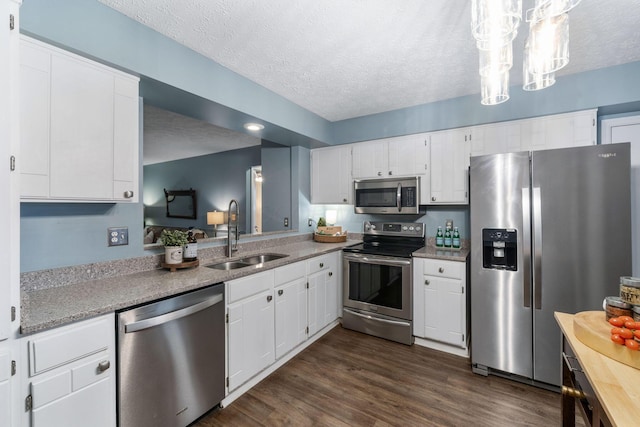 kitchen featuring stainless steel appliances, a sink, a textured ceiling, and dark wood-style floors