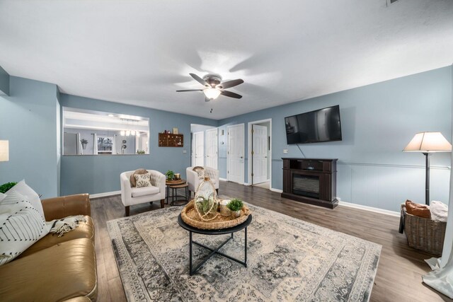 living area with ceiling fan, a fireplace, baseboards, and wood finished floors