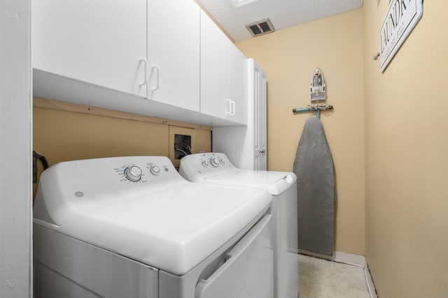 washroom featuring visible vents, cabinet space, and washer and clothes dryer