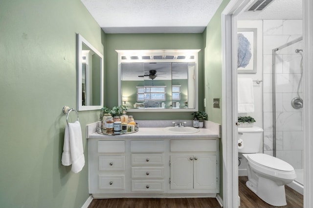 bathroom with a stall shower, visible vents, toilet, wood finished floors, and a textured ceiling