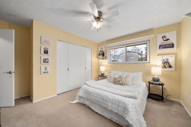 carpeted bedroom featuring a ceiling fan, a closet, a textured ceiling, and baseboards