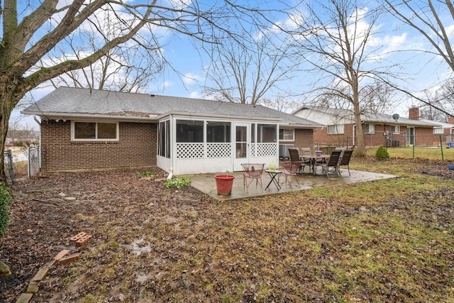 rear view of house with a sunroom, brick siding, a patio, and fence