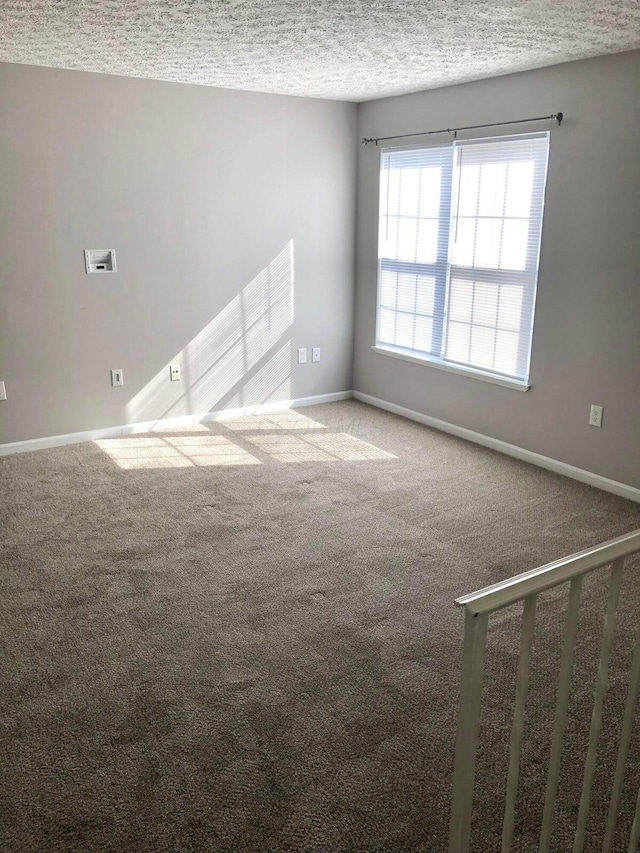 carpeted empty room featuring baseboards and a textured ceiling