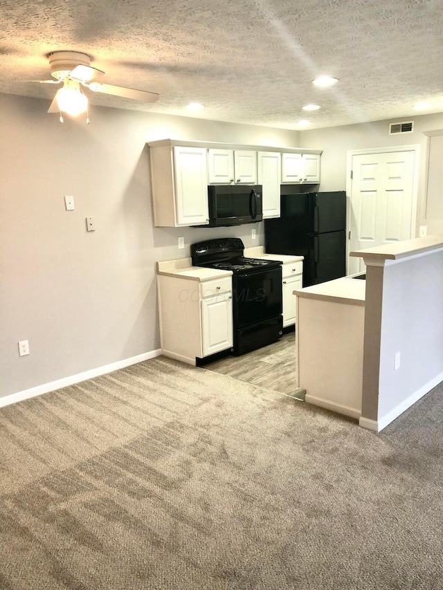 kitchen with visible vents, baseboards, light colored carpet, white cabinets, and black appliances