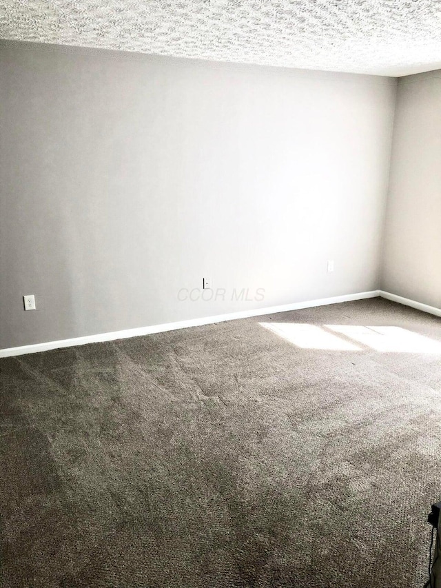 carpeted empty room featuring baseboards and a textured ceiling