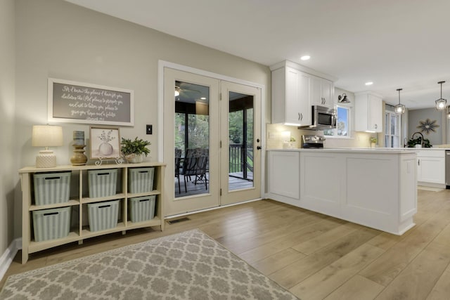 kitchen with light wood-style floors, a ceiling fan, stainless steel appliances, and white cabinetry