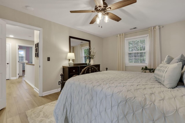 bedroom featuring baseboards, multiple windows, light wood-style flooring, and visible vents