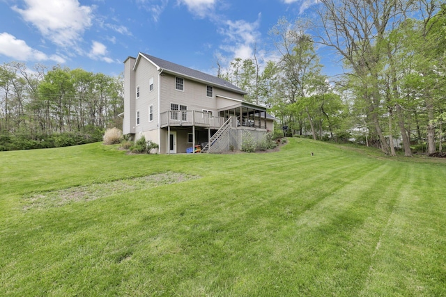 rear view of house featuring a lawn, stairway, and a deck