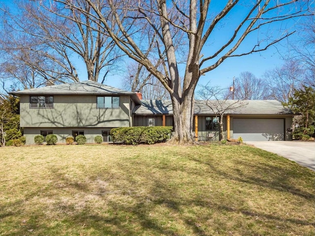 split level home with a chimney, an attached garage, concrete driveway, and a front lawn