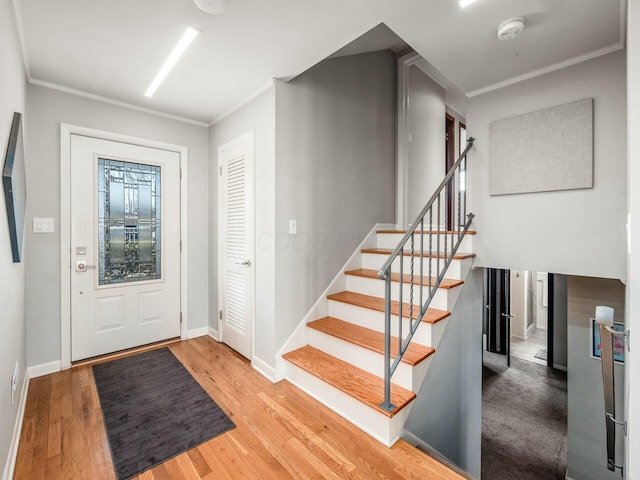 entrance foyer featuring stairway, ornamental molding, baseboards, and wood finished floors