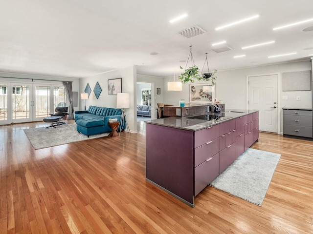 kitchen with light wood finished floors, visible vents, a center island, open floor plan, and french doors