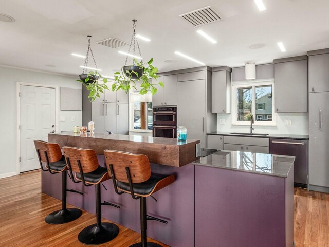 kitchen with a sink, visible vents, stainless steel dishwasher, and gray cabinetry