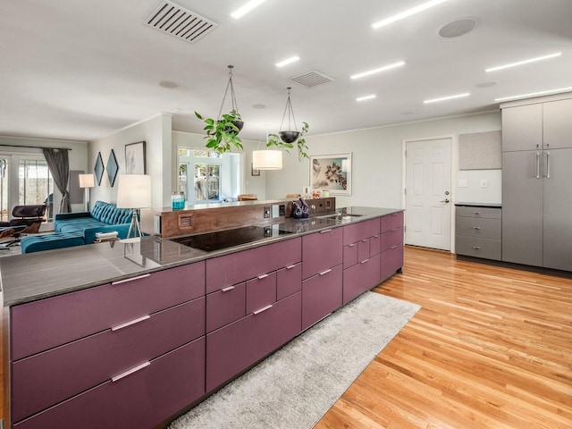 kitchen featuring visible vents, light wood-style flooring, modern cabinets, and black electric stovetop