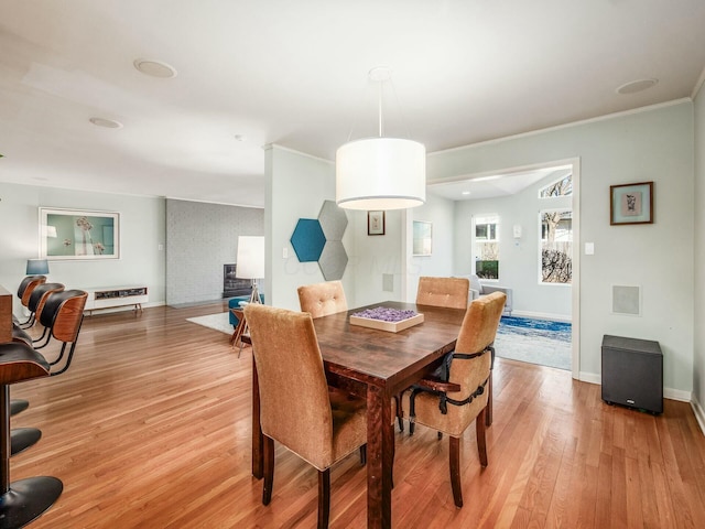 dining space featuring baseboards, crown molding, and light wood finished floors