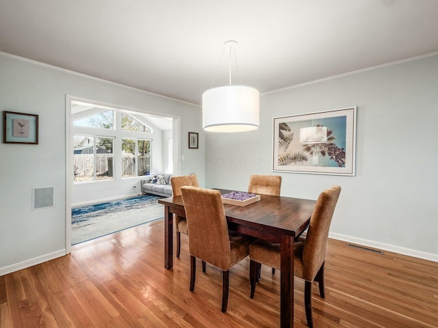 dining room with visible vents, baseboards, wood finished floors, and ornamental molding