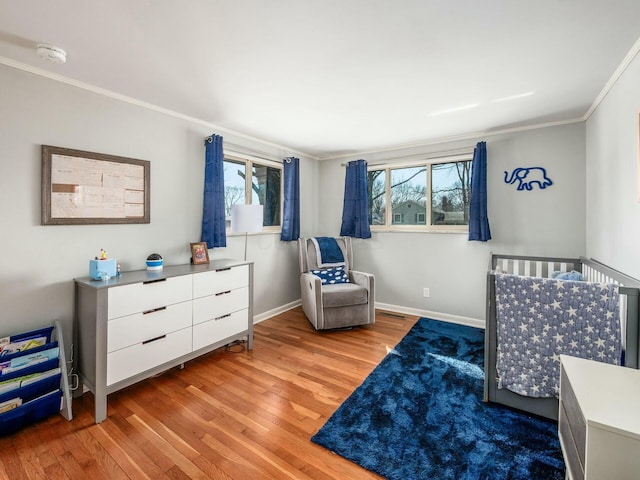 bedroom with baseboards, multiple windows, light wood-style floors, and ornamental molding