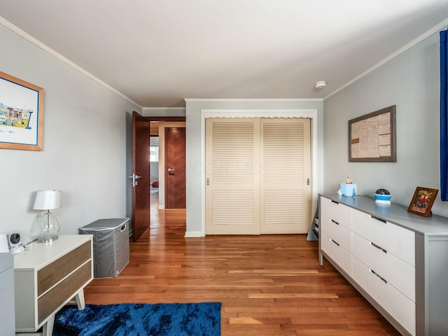 bedroom featuring a closet, light wood-type flooring, and ornamental molding