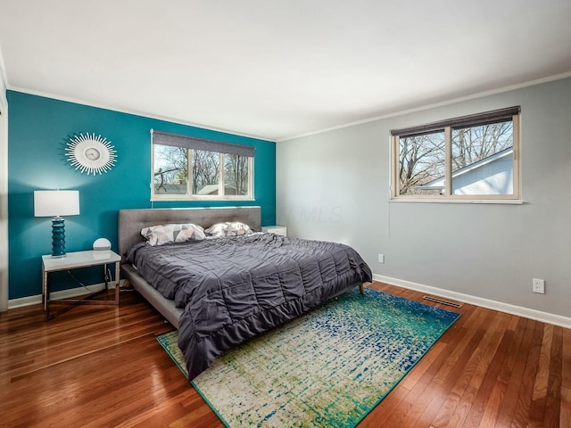 bedroom featuring visible vents, multiple windows, baseboards, and hardwood / wood-style flooring