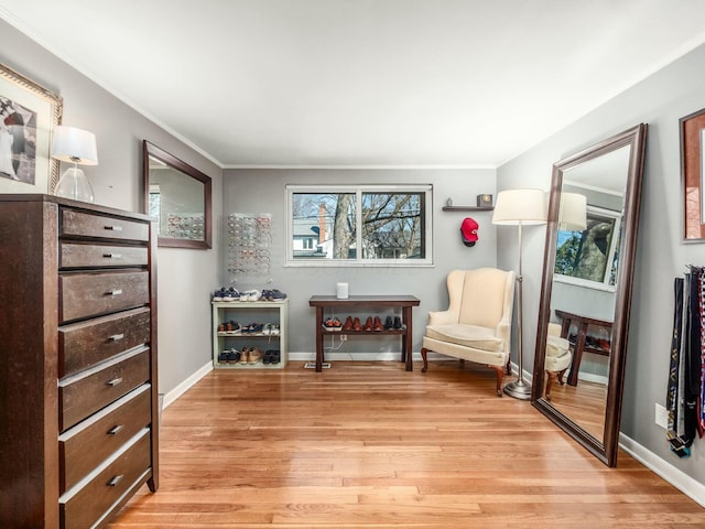 sitting room featuring baseboards, crown molding, and light wood finished floors