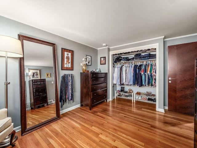 unfurnished bedroom with crown molding, baseboards, light wood-type flooring, and a closet