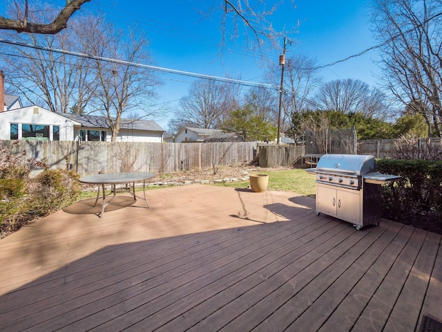 wooden terrace with a grill and a fenced backyard