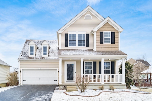 traditional-style house featuring covered porch, driveway, and an attached garage