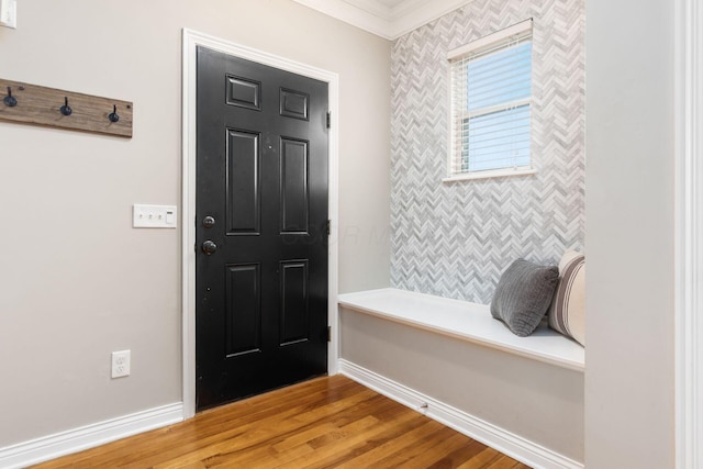 entrance foyer with an accent wall, baseboards, wood finished floors, and ornamental molding