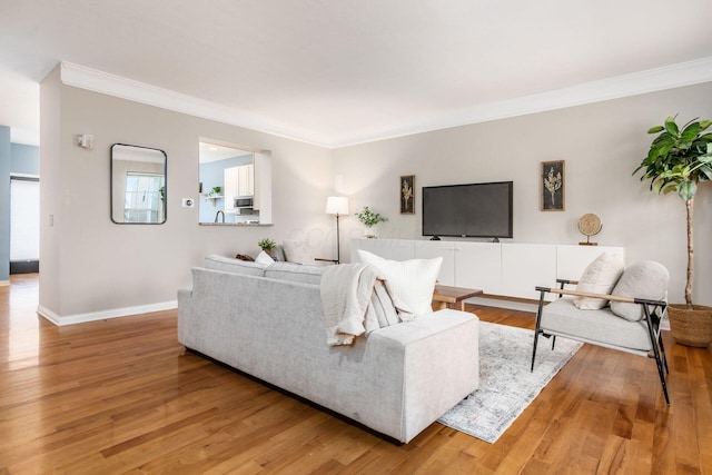 living room with crown molding, light wood-style flooring, and baseboards