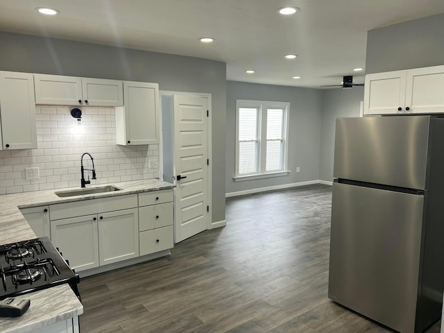 kitchen featuring tasteful backsplash, dark wood finished floors, white cabinets, freestanding refrigerator, and a sink