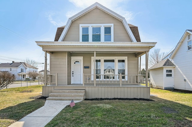 dutch colonial with a gambrel roof, roof with shingles, a porch, and a front yard