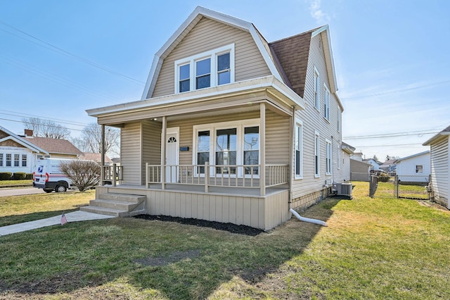 dutch colonial featuring a shingled roof, a porch, a gambrel roof, and a front lawn