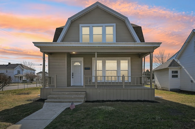 dutch colonial featuring a porch, a gambrel roof, and a front yard