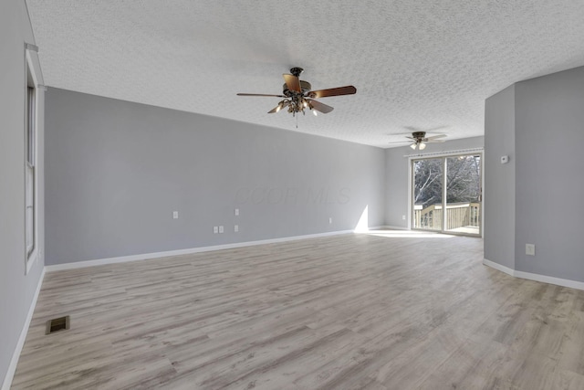 unfurnished room with visible vents, baseboards, ceiling fan, light wood-style floors, and a textured ceiling