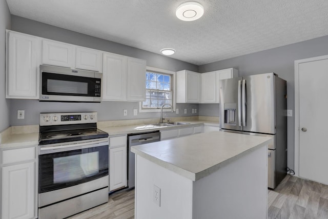 kitchen with a sink, appliances with stainless steel finishes, white cabinets, and light countertops