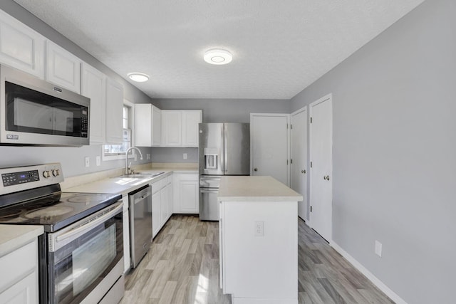 kitchen featuring a sink, a kitchen island, appliances with stainless steel finishes, white cabinets, and light countertops