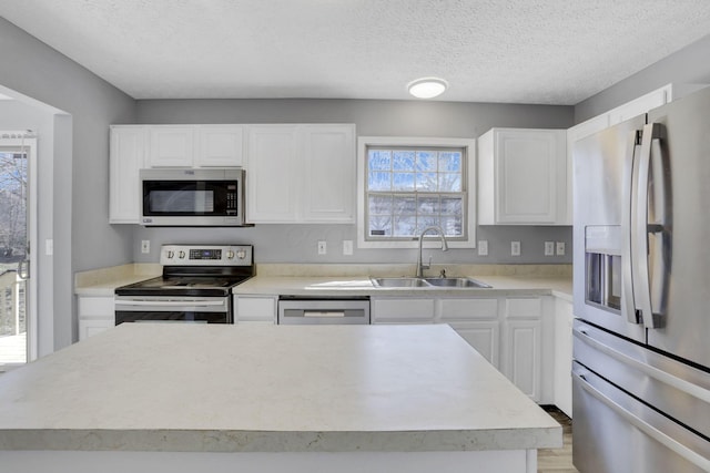 kitchen featuring white cabinets, stainless steel appliances, light countertops, and a sink