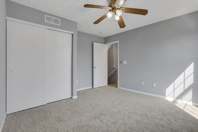 unfurnished bedroom featuring visible vents, baseboards, carpet flooring, a closet, and a textured ceiling