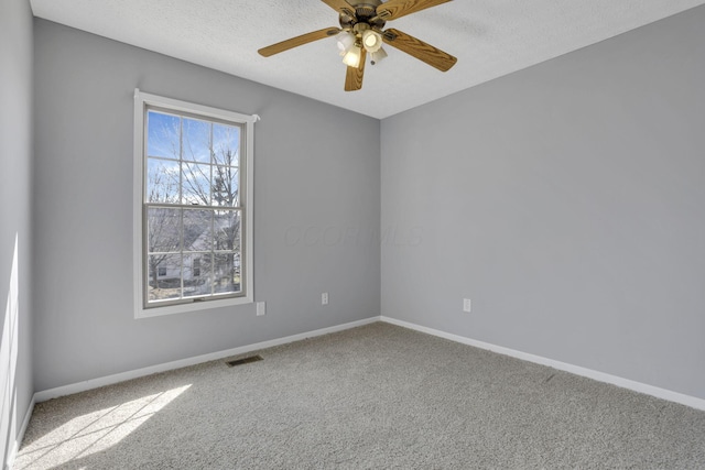 spare room featuring visible vents, baseboards, ceiling fan, carpet flooring, and a textured ceiling