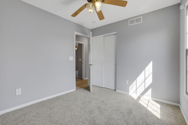 unfurnished bedroom featuring baseboards, visible vents, carpet floors, ceiling fan, and a closet