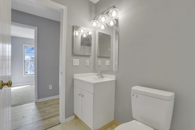 bathroom featuring baseboards, toilet, and vanity