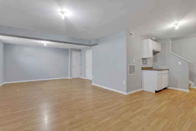 unfurnished living room featuring light wood-type flooring, visible vents, and baseboards