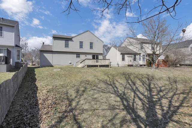 rear view of house with a wooden deck, a yard, and fence