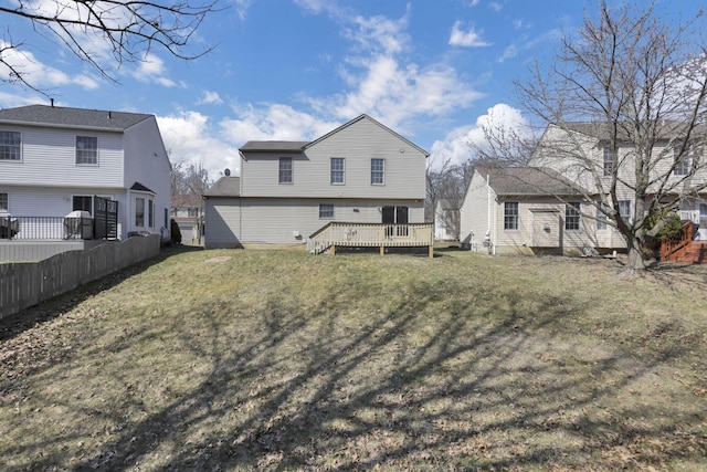 rear view of property featuring a wooden deck, a yard, and fence