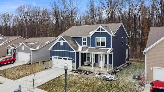 view of front facade featuring driveway, an attached garage, covered porch, a shingled roof, and board and batten siding